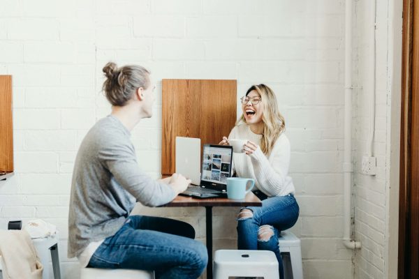 a happy woman laughs with her friend sat at a table